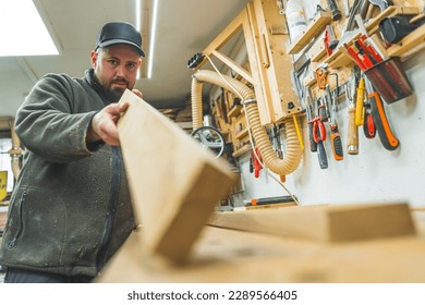 Professional carpenter holding wooden plank to the camera and measuring by eye. Carpentry and woodworking concept. High quality photo - Powered by Shutterstock