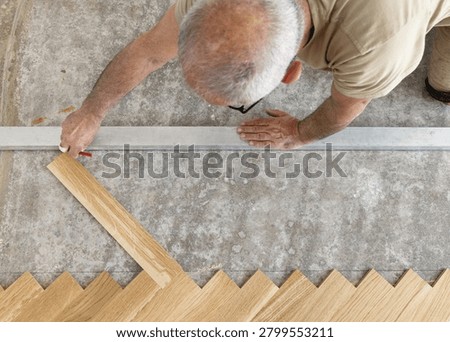 Professional carpenter measuring and marking layout for Italian herringbone parquet flooring before installation, top view. Hardwood flooring work in apartment renovation and interior finishing