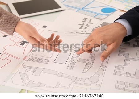 Professional cartographers working with cadastral map at table, closeup