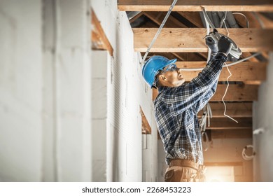 Professional Caucasian Electrician Working on Electrical Wiring System Installation in New Residential House Ceiling. - Shutterstock ID 2268453223
