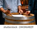 Professional Caucasian man and woman sommelier winemaker tasting and smelling red wine in wine glass at wine cellar or liquor shop. Winery, brewery manufacturing factory industry and business concept.