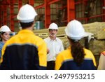 Professional Caucasian manager engineer wearing safety hardhat is training industry worker, workshop factory operator, mechanical engineering team production in heavy industrial manufacture factory.