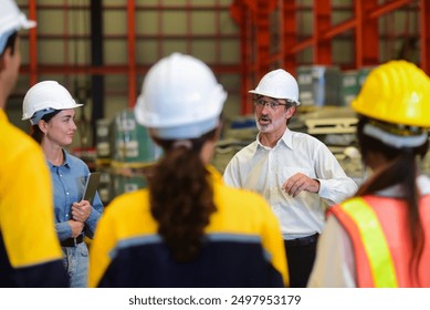 Professional Caucasian manager engineer wearing safety hardhat is training industry worker, workshop factory operator, mechanical engineering team production in heavy industrial manufacture factory.