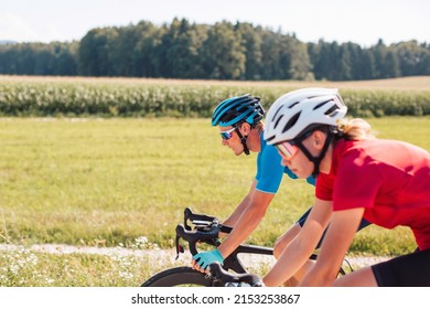 Professional Caucasian racing cyclists couple riding on an asphalt road in the countryside, tracking shot.