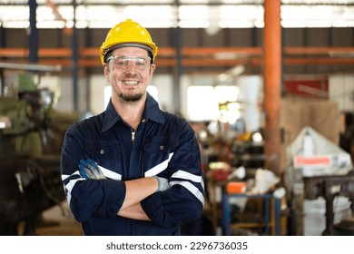 Professional caucasian white ethnicity male technician operating the heavy duty machine in the lathing factory. Technician in safety and helmet suit controlling a machine in factory. - Powered by Shutterstock