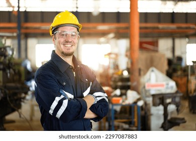 Professional caucasian white ethnicity male technician operating the heavy duty machine in the lathing factory. Technician in safety and helmet suit controlling a machine in factory.