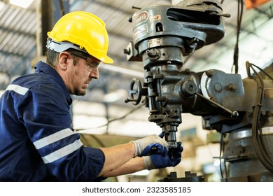 Professional caucasian white ethnicity male technician operating the heavy duty machine in the lathing factory. Technician in safety and helmet suit controlling a machine in factory. - Powered by Shutterstock