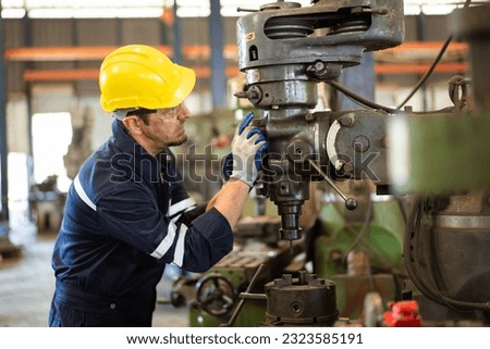 Professional caucasian white ethnicity male technician operating the heavy duty machine in the lathing factory. Technician in safety and helmet suit controlling a machine in factory.