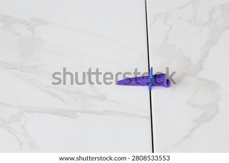 Professional ceramic tile installation. The process of leveling white marble tiles using a plastic wedge and clip. Tile leveling system. Using plastic clamps to control the inter-tile seam and plane. Repair