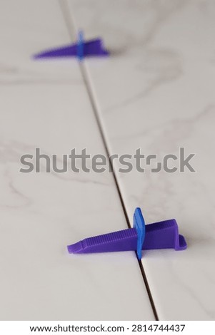 Professional ceramic tile installation. The process of leveling white marble tiles using a plastic wedge and clip. Tile leveling system. Using plastic clamps to control the inter-tile seam and plane. Repair