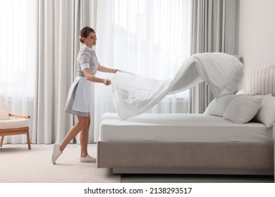 Professional chambermaid making bed in hotel room