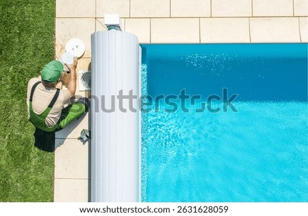 A professional is checking the pool water quality beside a sparkling blue pool in a residential backyard. The grass is lush and green, indicating a warm, sunny day.