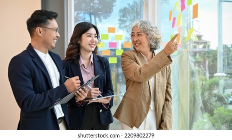 Professional And Cheerful Senior Asian Female Boss Training And Giving Project Advice To Her Employees.