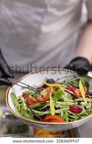 Professional chef adding final touches to a vibrant salad, close up