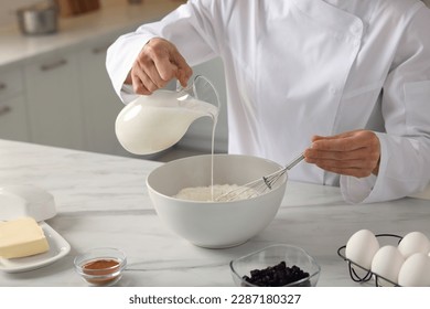 Professional chef adding milk into dough at white marble table indoors, closeup - Powered by Shutterstock