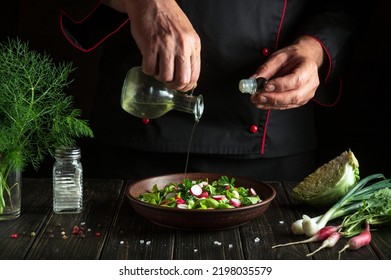 Professional chef adds vegetable oil to a plate with a delicious salad. Diet dinner or lunch