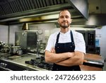 Professional chef with arms crossed in the kitchen looking at camera. Copy space.