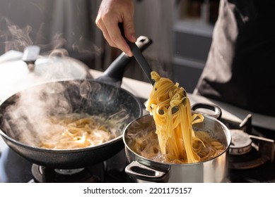 Professional chef cook making Italian Tagliatelle pasta with mushrooms and cream at modern kitchen gas stove in wok pan and pot. - Powered by Shutterstock