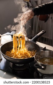 Professional Chef Cook Making Vegetarian Italian Tagliatelle Pasta With Mushrooms And Cream At Modern Kitchen Gas Stove In Wok Pan.