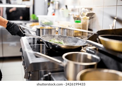 Professional chef cooking asparagus in frying pan on stove in restaurant kitchen - Powered by Shutterstock