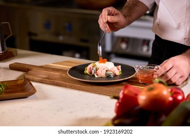 Professional chef cooking in kitchen restaurant at hotel, preparing dinner. cook in apron makes salad adding red caviar - Powered by Shutterstock