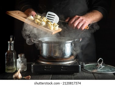 Professional chef cooks dumplings in a saucepan in the kitchen. Close-up of the hands of cook during work
