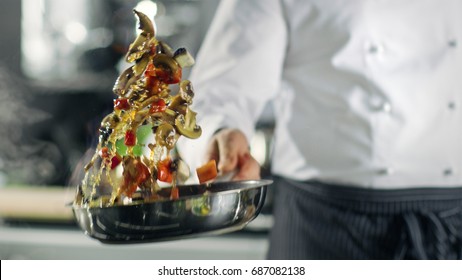 Professional Chef Cooks Flambe Style. He Prepares Dish in a Pan with Open Flames. He Works in a Modern Kitchen with Different Ingredients Lying Around. - Powered by Shutterstock