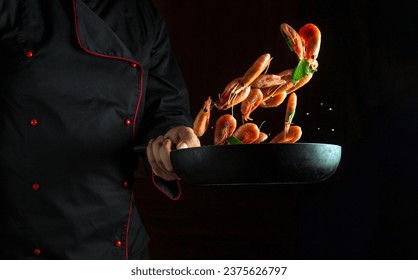 Un chef profesional cocina camarones en una sartén con perejil. Cocina de marisco o comida vegetariana saludable y comida con un fondo oscuro. Congelar en movimiento. Espacio publicitario gratuito.