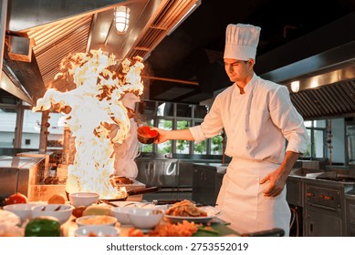 Professional chef creating flambé flame while cooking in a restaurant kitchen. Concept of high heat cooking, culinary performance, gastronomy technique and professional restaurant environment.