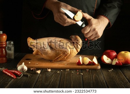 Professional chef cuts an apple before adding it to a raw duck for roasting in the oven. Cooking a national dish in the restaurant kitchen by the cook hands