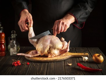 Professional Chef Cuts Raw Broiler Chicken Before Preparing Dinner. Work Environment On The Kitchen Table. Hotel Chicken Menu Idea