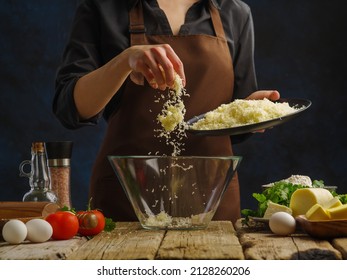 A professional chef in a dark uniform mixes grated cheese, vegetables, herbs, eggs in a glass bowl. The concept is cooking a salad. Vitamins, dietary, vegetarian, low calorie food. Restaurant, hotel. - Powered by Shutterstock