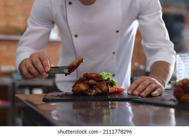 Professional chef with delicious fried chicken wings in restaurant kitchen, closeup - Powered by Shutterstock