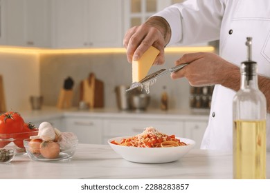 Professional chef grating cheese into delicious dish at white marble table indoors, closeup. Space for text - Powered by Shutterstock