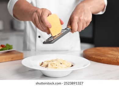 Professional chef grating cheese into delicious dish at white marble table in kitchen, closeup - Powered by Shutterstock