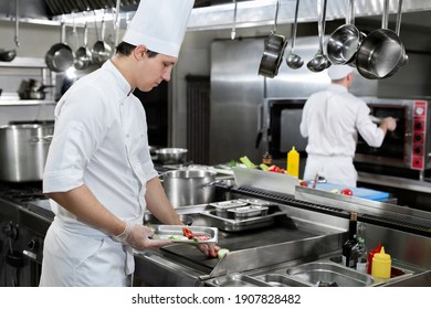 Professional chef in the kitchen roasts vegetables on the grill - Powered by Shutterstock