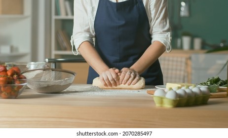 Professional Chef Kneads Dough for Baking on a Wooden Kitchen Table. The Process of Making a Beautiful Dough. Homemade Cakes for a Pastry Coffee Shop. Close-up.