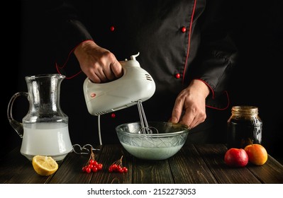 Professional chef making milk fruit shake with electric hand mixer or appliance. Menu for a restaurant or hotel. Work environment on kitchen table.