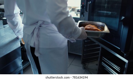 Professional Chef Man Put Meat Dish Into Oven At Restaurant Kitchen