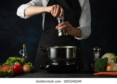 Professional chef pours spices into boiling water in the pot on variety of ingredients background. Backstage of preparing appetizing food. Concept of cooking process. Frozen motion. - Powered by Shutterstock