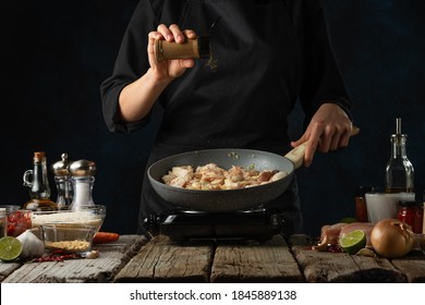 Professional chef pours spices to pan wok with frying chicken. Backstage of cooking traditional Indian chicken curry on dark blue background. Frozen motion. Concept of cooking tasty hot meal. - Powered by Shutterstock