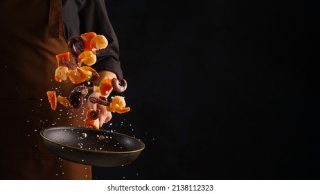 A professional chef prepares assorted seafood - octopus, shrimp and pieces of red fish. Seafood in frozen flight on a black background. Sea food. Healthy food, vegetarian food. - Shutterstock ID 2138112323