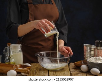 A professional chef prepares dough in a bowl on a wooden kitchen table. He pours milk into a bowl. Levitation. Lots of ingredients. Cooking dishes from dough, recipes for restaurant and home cooking. - Powered by Shutterstock