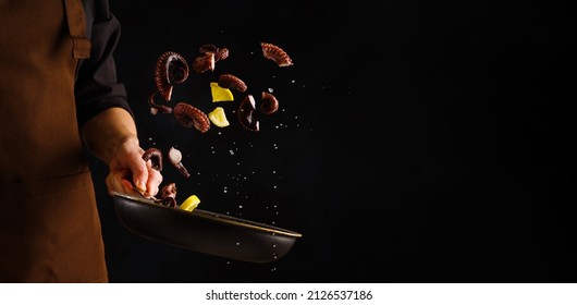 A professional chef prepares octopus with lemon slices in a frying pan on a black background. Levitation. Healthy vegetarian food, gourmet food. Restaurant, hotel. - Shutterstock ID 2126537186