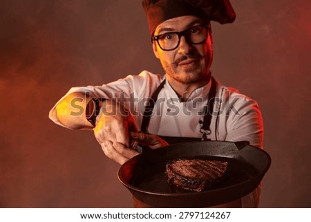 Professional chef presenting a freshly cooked steak in a cast iron skillet with dramatic lighting. Restaurant cuisine and grilling concept.
