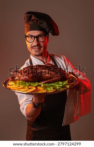 Professional chef presenting a roasted duck garnished with fresh lettuce and orange slices. Gourmet cuisine, holiday dinner and restaurant food concept.