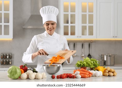 Professional chef putting cut bell pepper into metal bowl at white marble table in kitchen - Powered by Shutterstock