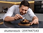 Professional chef serving dish at table indoors