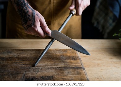 Professional Chef Sharpening Knife In The Kitchen