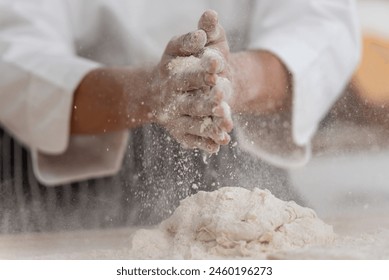 professional Chef sifting flour powder and sprinkling ingredients on massaging dough for bakery cooking. Chef show dirty finger hand sifting flour wheat and kneading dough mixing powder.